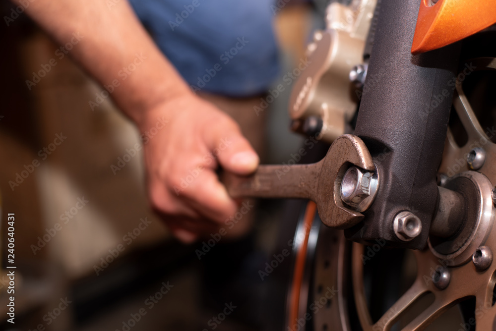 Obraz premium Mechaniker repariert sein Motorrad mit einem Schraubenschlüssel