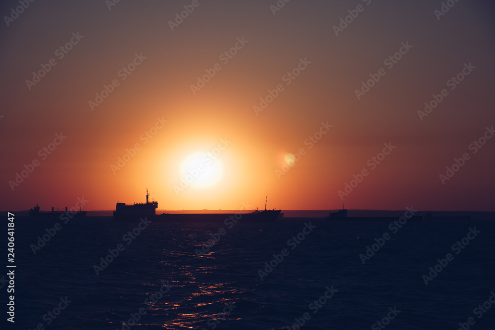 cargo ship outgoing from port at sunrise