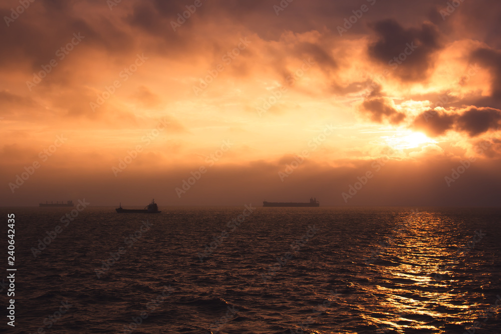 cargo ship outgoing from port at sunrise