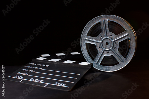 Clapperboard and film reel on black
