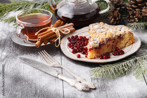 Traditional Christmas cake with dried fruits, raisins and a cup of tea on a wooden table with Christmas decorations