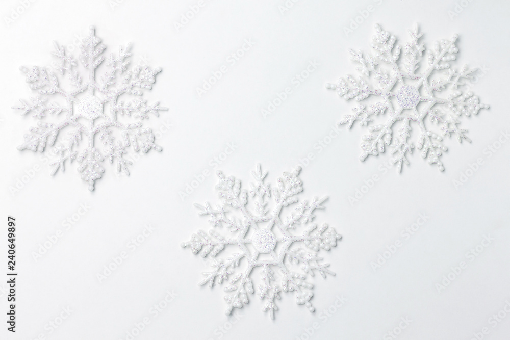 Plakat Three shiny white snowflakes on pure white background. Copy paste. Top view.
