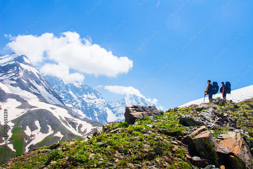 Climbers look at rocky summit covered by snow Climbers look at rocky summit covered by snow