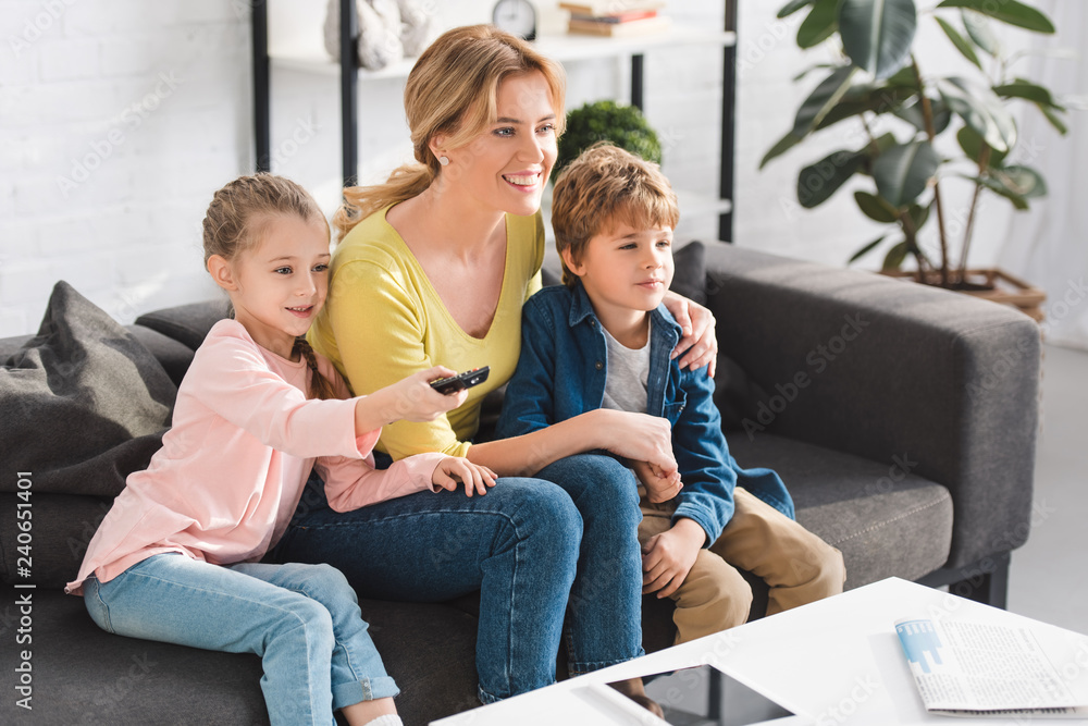 © LIGHTFIELD STUDIOS - happy mother and cute smiling kids using remote controller and watching tv together © LIGHTFIELD STUDIOS - happy mother and cute smiling kids using remote controller and watching tv together