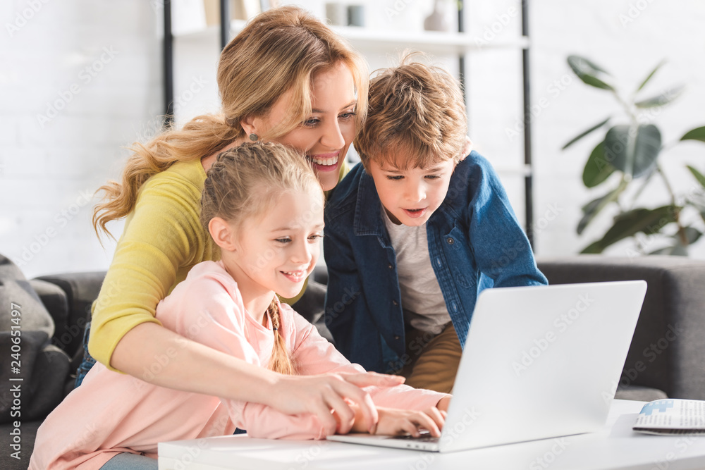 happy mother with adorable smiling kids using laptop together at home happy mother with adorable smiling kids using laptop together at home