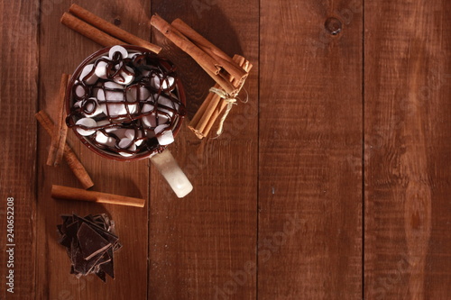 Cocoa, marshmallow, cinnamon sticks and pieces of chocolate on vintage wooden table. Coffee shop or desserts concept. Blue cup, winter drink, top view, confection