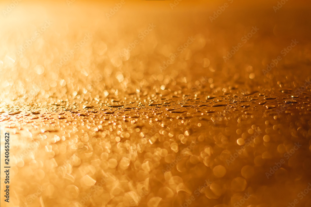 drops of a rain flow down on the smooth surface of golden metal in light sunshine drops of a rain flow down on the smooth surface of golden metal in light sunshine