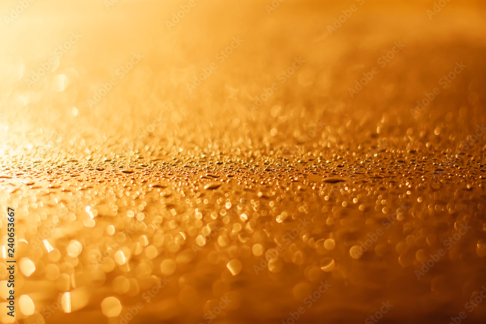 drops of a rain flow down on the smooth surface of golden metal in light sunshine drops of a rain flow down on the smooth surface of golden metal in light sunshine