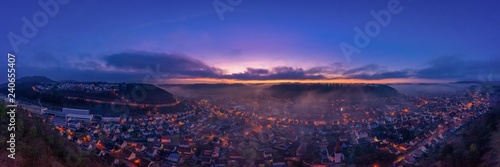 Nebliges Panorama der Schwäbischen Alb zur Abendstunde mit belichteten Häusern zum Sonnenuntergang als Luftaufnahme einer Drohne