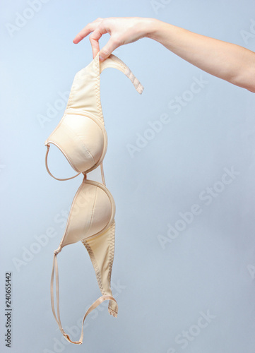 Cuadro en lienzo Female hand holding beige bra on gray background.
