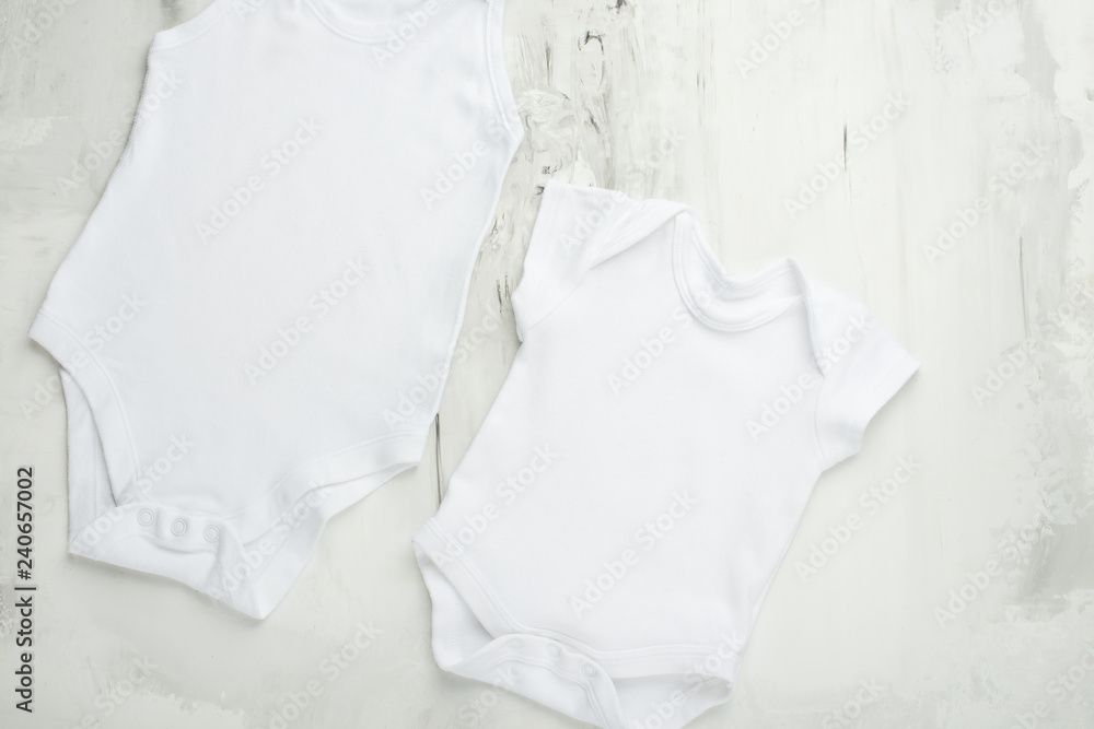 Layout Flat Put on a two white baby body shirt, on a white marble background. Layout for design and placement of logos, advertising Layout Flat Put on a two white baby body shirt, on a white marble background. Layout for design and placement of logos, advertising