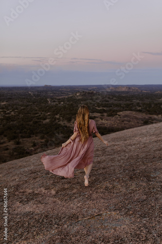 woman in dress running through the desert at sunset
