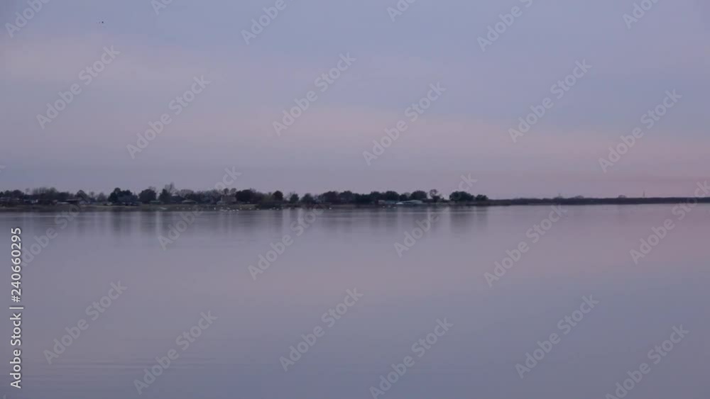 View of pelicans flying to the lake and their reflections on the water at sunset. View of pelicans flying to the lake and their reflections on the water at sunset.