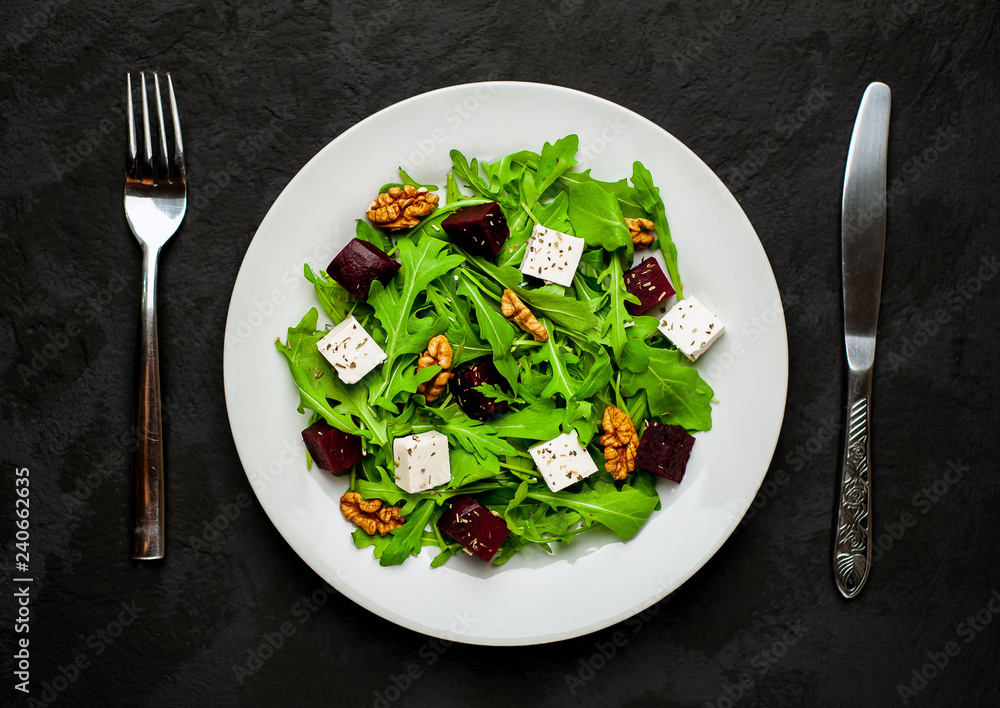 Salad of arugula, cheese, beet, walnut, on the background of slate, stone or concrete. Salad of arugula, cheese, beet, walnut, on the background of slate, stone or concrete.