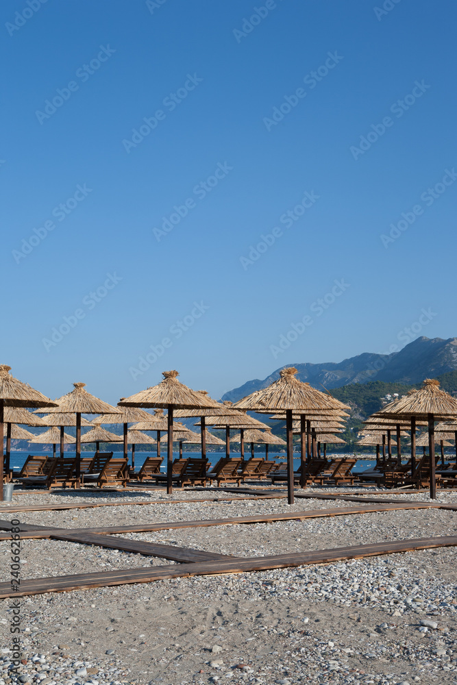 Bamboo umbrellas and wooden deck chairs on the sandy beach by the sea