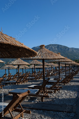 Fototapeta Naklejka Na Ścianę i Meble -  Bamboo umbrellas and wooden deck chairs on the sandy beach by the sea