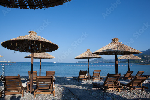 Bamboo umbrellas and wooden deck chairs on the sandy beach by the sea photo