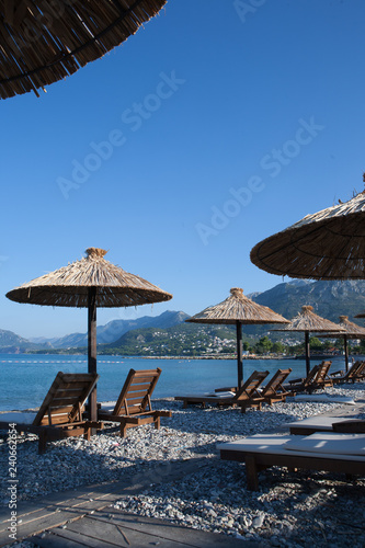 Bamboo umbrellas and wooden deck chairs on the sandy beach by the sea photo