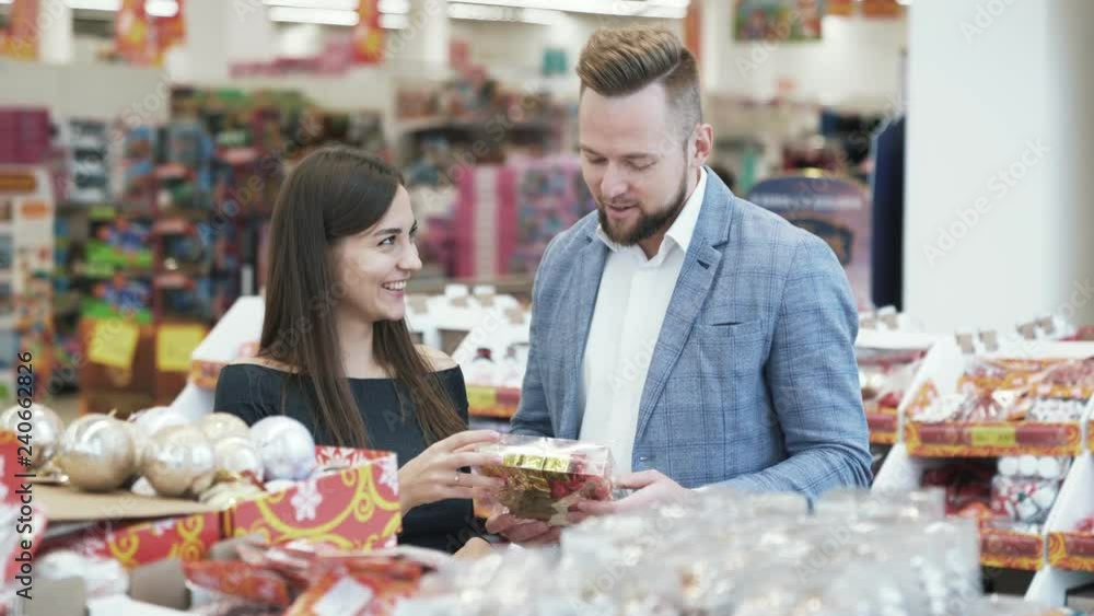 Happy young man and woman choose Christmas decorations in store. Happy young man and woman choose Christmas decorations in store.
