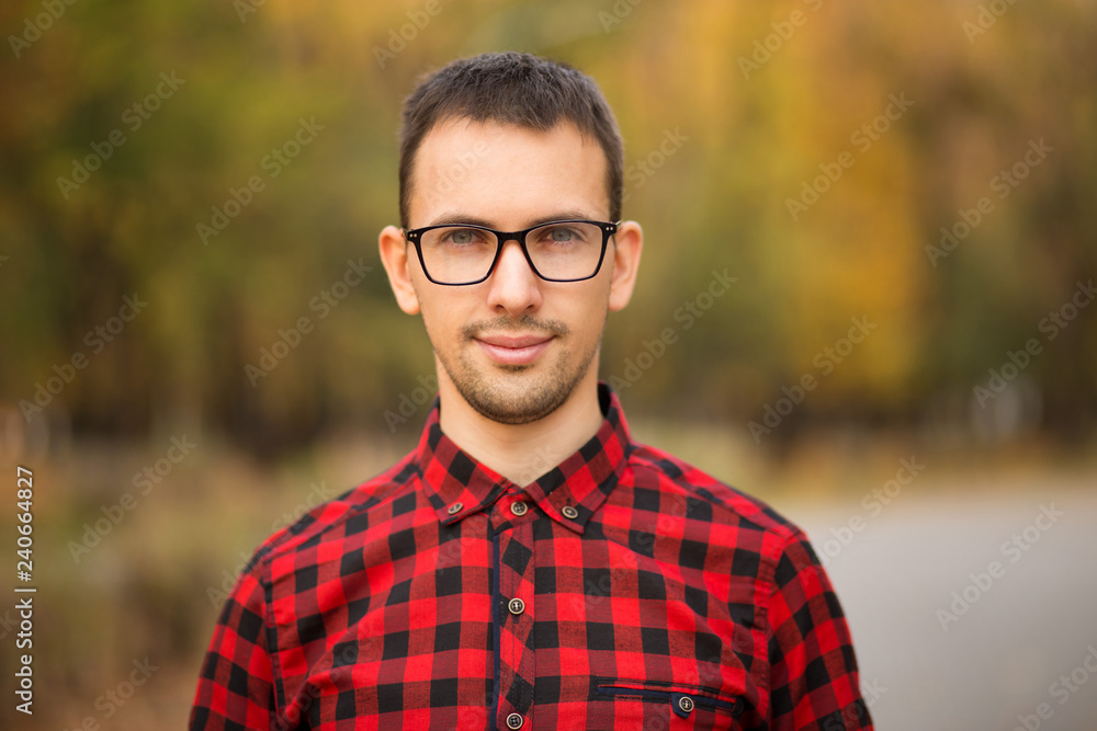Beautiful young financial businessman in glasses looking at camera and smiling while standing in park after business meeting. Beautiful young financial businessman in glasses looking at camera and smiling while standing in park after business meeting.