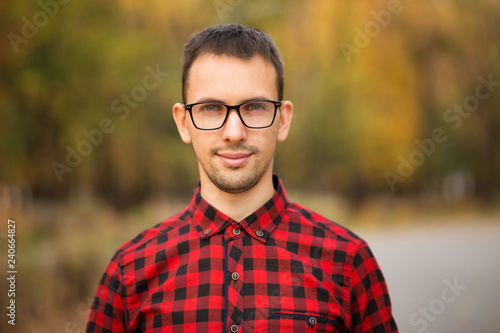 Beautiful young financial businessman in glasses looking at camera and smiling while standing in park after business meeting.
