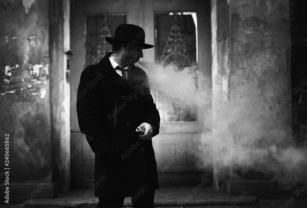 Vape man. Portrait of a handsome young white guy in a black hat vaping and letting off puffs of steam from an electronic vaponizer