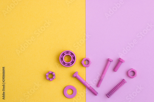 Metal robot, screws and washers, spring, colored with multicolored paint. Colorful background. Pink and yellow. Concept, background, flat lay. Free space for text.