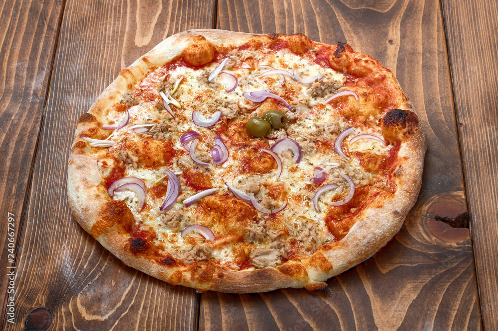 Tuna and red onion pizza on wooden background, side view