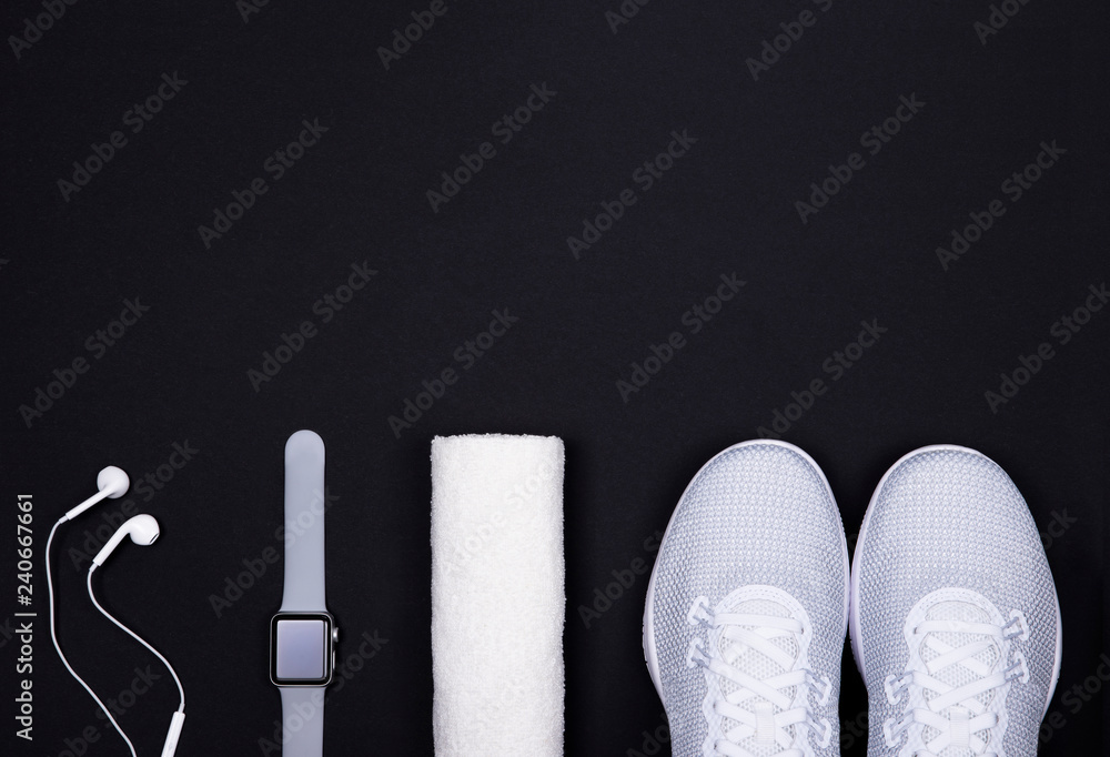 White sport shoes (sneakers) with smart watch (activity tracker), towel and  earphones (headphones) on black color background. foto de Stock | Adobe  Stock