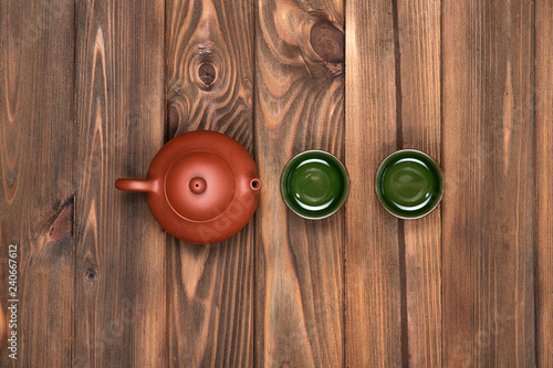 Brown ceramic teapot and two dark green small special cups on a dark wooden planked background. Tea ceremony. 