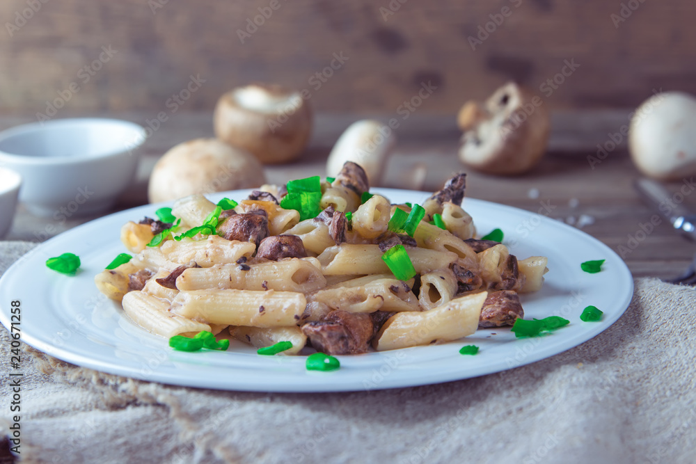 Delicious Italian penne pasta with fried creamy mushrooms champignon , onion, seasoned chopped scallions. Healthy concept