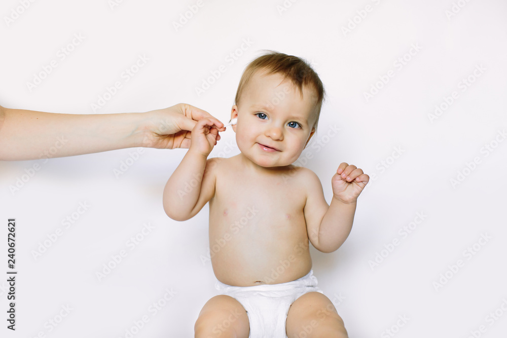 Mother hand cleaning small baby ear with cotton swab, closeup Mother hand cleaning small baby ear with cotton swab, closeup
