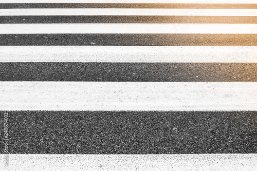  parallel lines of crosswalk, asphalt rough pattern, no people, sunlight in one corner