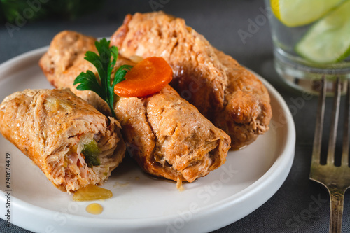 Pork roulades with bacon, carrot, cucumber and onion served on plate.