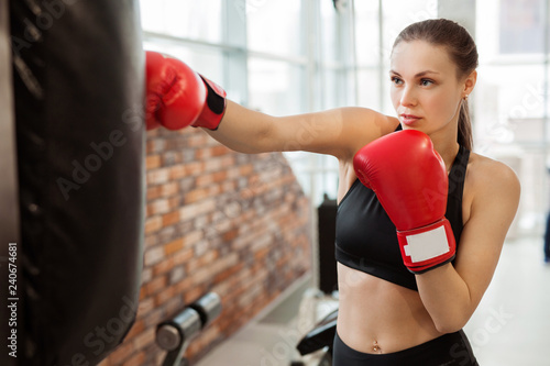 beautiful young girl in red boxing gloves is engaged in training in the gym