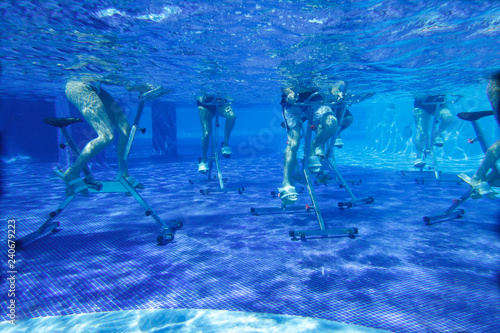 Touristen doing aqua aerobics on exercise bikes in swimming pool tropical hotel