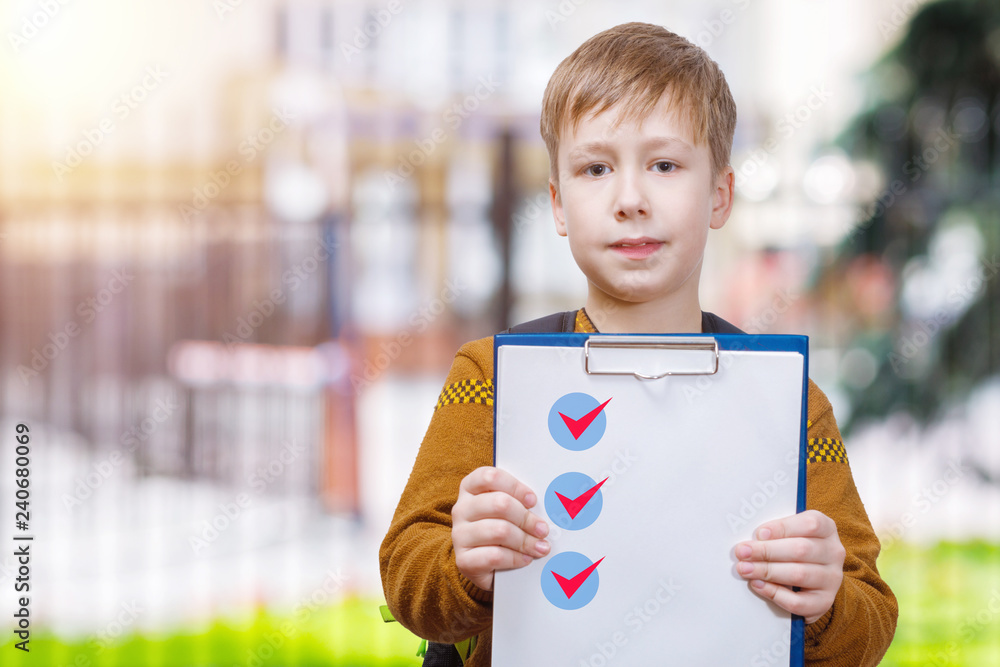 A pupil with a list of done tasks in his hands. A pupil with a list of done tasks in his hands.