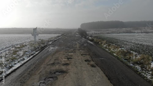 Cyclist rides on road with a lot of potholes and pits. Aerial view, smooth rise up