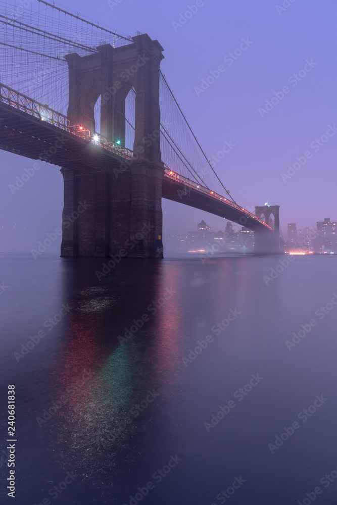 Fototapeta premium View on Brooklyn Bridge from east river on a foggy night with long exposure