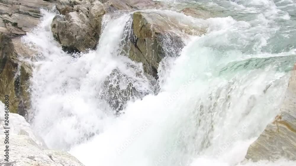 Slow motion close up of water rushing past ig rocks and heading down fast paced waterfall Slow motion close up of water rushing past ig rocks and heading down fast paced waterfall