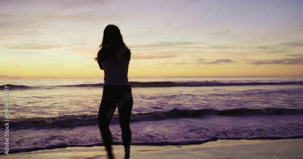 Woman silhouette - beach running, skipping, splashing in ocean water during sunset Woman silhouette - beach running, skipping, splashing in ocean water during sunset