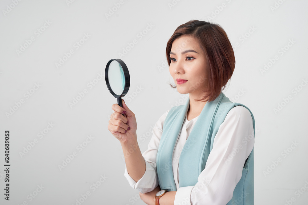 Close-up portrait of cheerful woman in blue suite looking at camera through magnifying glass, isolated over white background Close-up portrait of cheerful woman in blue suite looking at camera through magnifying glass, isolated over white background