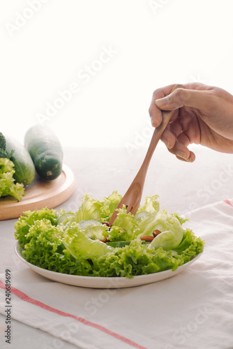 Green vegan breakfast meal in bowl with lettuce, cucumber, lime and almond. Girl holding plate with hands visible, top view. Clean eating, dieting, vegan food concept