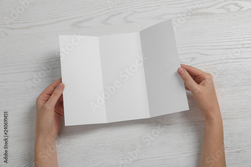 Woman with blank brochure on wooden background, above view. Mock up for design © New Africa