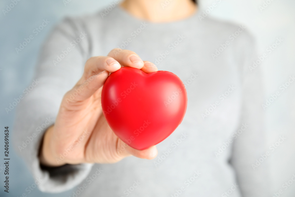 Woman holding red heart against color background, closeup. Cardiology concept