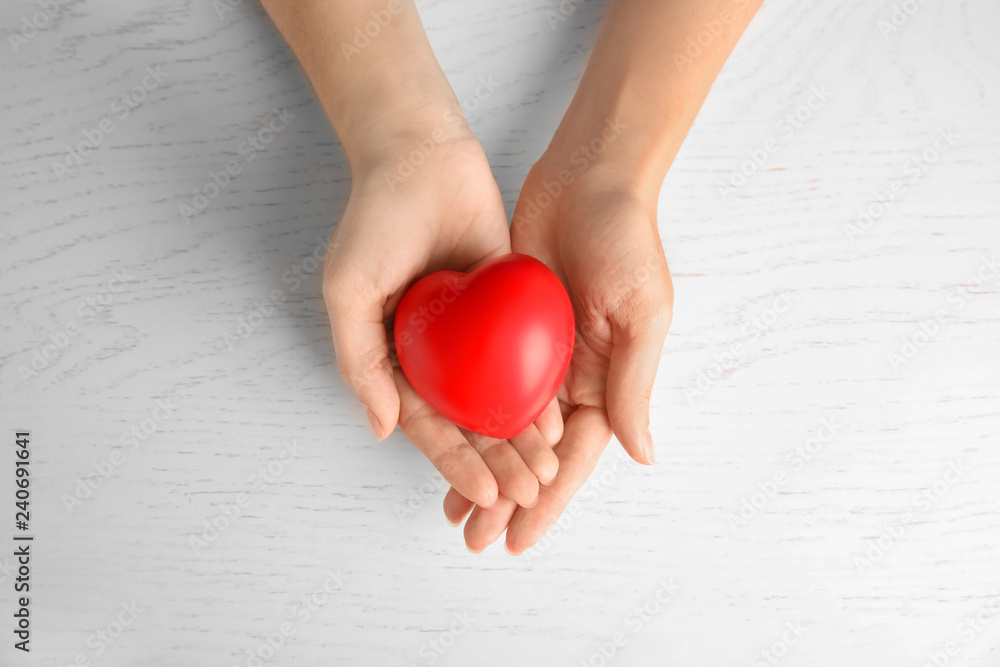 Woman holding red heart on wooden background, top view. Cardiology concept Woman holding red heart on wooden background, top view. Cardiology concept