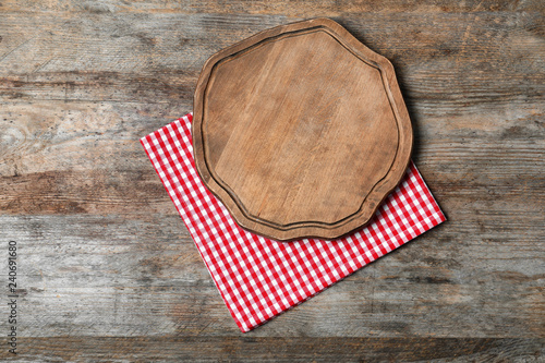 Fabric napkin with serving board and space for text on wooden background, top view