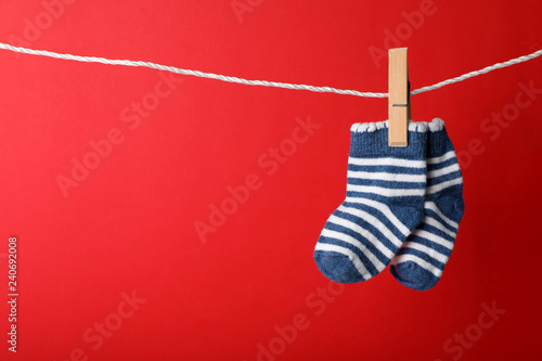 Cute child socks on laundry line against color background. Space for text