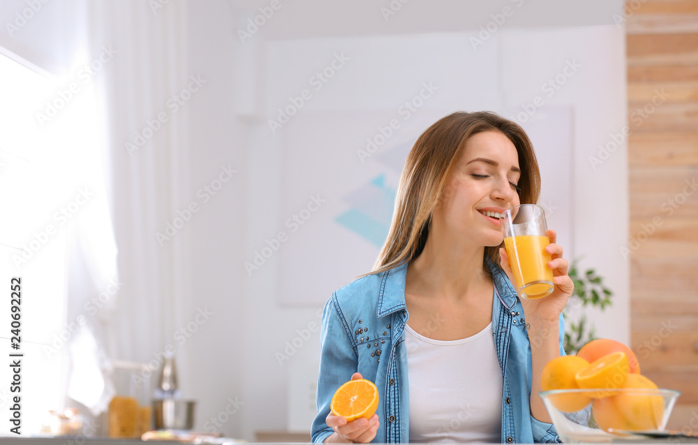 Beautiful young woman drinking orange juice at table indoors, space for text. Healthy diet Beautiful young woman drinking orange juice at table indoors, space for text. Healthy diet