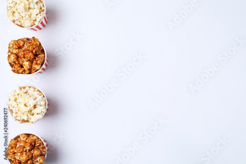 Different kinds of popcorn in paper cups on white background, top view. Space for text